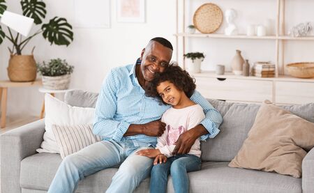 African American family of granddad and granddaughter embracing indoors. Panorama