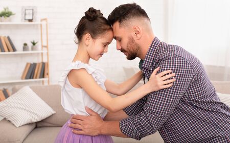 Daddys love. Loving dad embracing his cute little daughter at home, side viewの写真素材