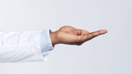 Outstreched black doctor hand over white background, cropped, side view, panoramaの写真素材