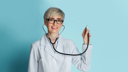 Beautiful woman doctor with glasses listens through stethoscope, free spaceの写真素材