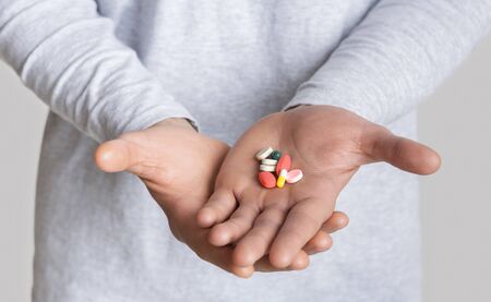 Drug treatment. Many bright pills on hand, cropped