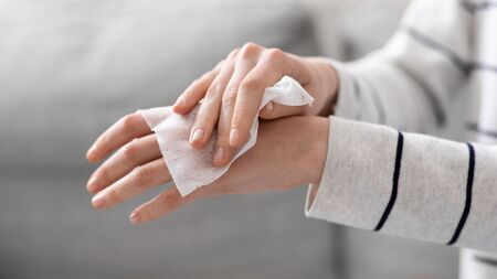 Personal hygiene. Woman disinfecting hands with antibacterial alcoholic napkins, close up
