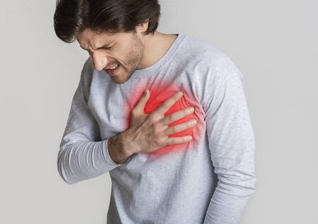 Heart disease concert. Man holds chest, highlighted in red, free space