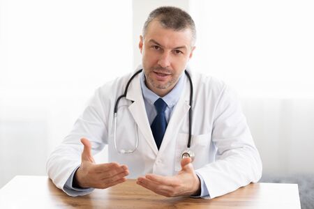 Physician Office Visit Concept. Portrait of male doctor talking to camera, gesturing, consulting...
