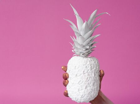 Hand holds white pineapple on pink background, free spaceの写真素材