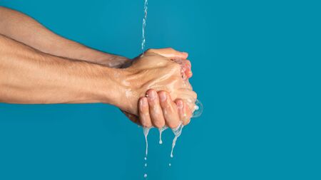 Protection from coronavirus. Unrecognizable millennial guy washing his hands with soap on blue...