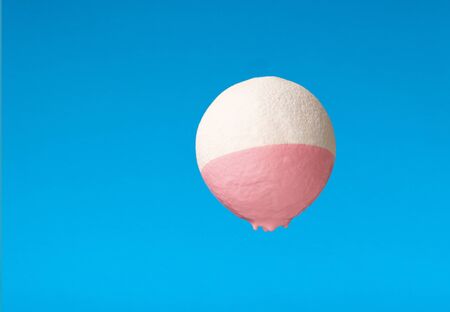 Minimalism and creative concept. Pink paint dripping from white orange on blue backgroundの写真素材