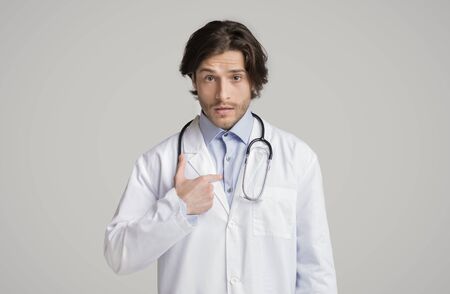 Puzzled male therapist pointing at himself with questionnaire face expression and looking at camera, white background with copy spaceの写真素材