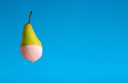From green pear dripping paint on blue background, free space