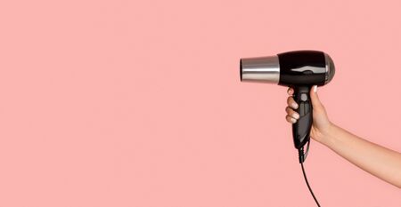 Unrecognizable girl showing hairdryer on pink background, copy space. Panoramaの写真素材