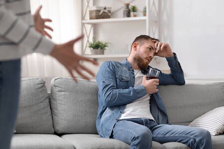 Alcoholism problem. Angry woman quarreling with her drinking husband at homeの写真素材