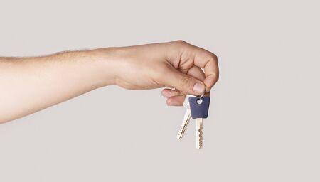 Male hand holding house keys on light background, close up. Panoramaの写真素材
