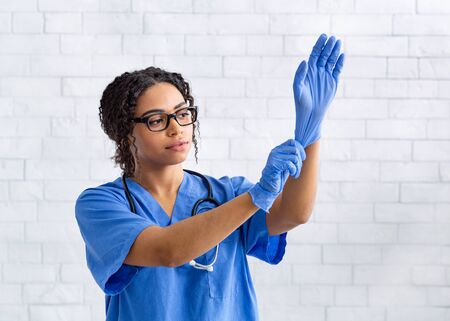 Female African American vet doctor putting on rubber gloves in animal hospital, copy spaceの写真素材
