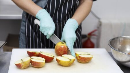 Woman in rubber gloves cutting apples for preparing healthy food for take away, quarantine delivery, panoramaの写真素材