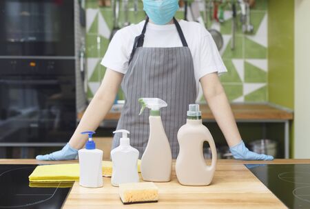 Woman in mask and gloves showing all eco detergents for kitchen disinfection, quarantine, cleaning conceptの写真素材
