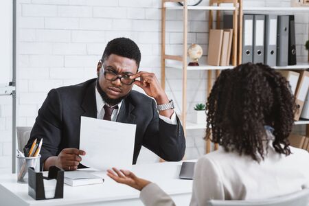 Searching for work concept. Serious human resources manager looking through applicants resume on job interview in officeの写真素材
