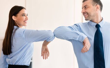 Social-Distancing Business Greeting. Businesswoman And Businessman Bumping Elbows At Work Standing In Officeの写真素材