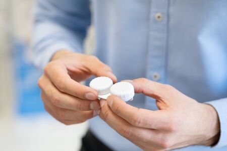 Close up of unrecognizable man holding contact eye lenses container, selective focus