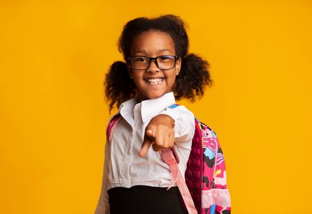 Hey, You. Smiling African Schoolgirl Pointing Finger At Camera Standing On Yellow Background. Studio Shotの写真素材