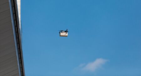 Air transportation. Automatic drone with package in the city, concept of futuristic delivery, sky backgroundの写真素材