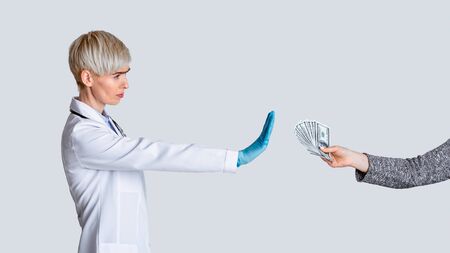 Bribe concept. Strict doctor dont takes money of patient, isolated on light background, studio shotの写真素材