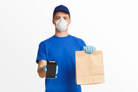 Contactless delivery during coronavirus quarantine concept. Courier in blue uniform holding package...