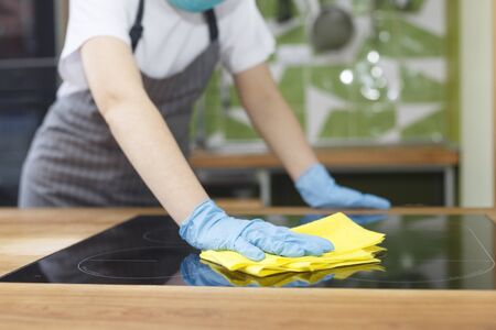 Unrecognizable young woman disinfecting kitchen counter with microfiber before starting cooking