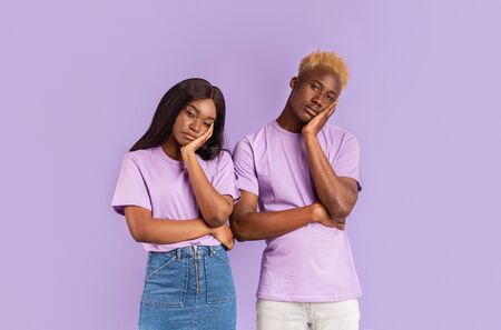 Bored African American couple with dull facial expressions on lilac backgroundの写真素材