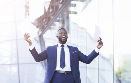 Business Success Concept. Excited Businessman Shouting In Joy Throwing Papers Celebrating Promotion At Work Standing Outdoors In City.の写真素材
