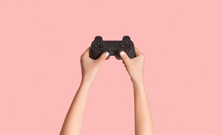 Fun hobbies concept. Woman holding video game joystick on pink background, closeup. Panorama