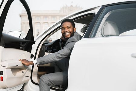 Car Rental. African American Businessman Opening Automobile Door Getting Out Of Auto In City.の写真素材