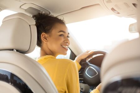 Own Car. Cheerful Black Woman Driving Auto Sitting In Drivers Seat In Automobile. Back View,...