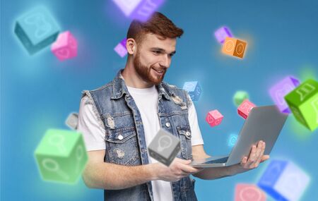 Collage of handsome guy working on laptop computer and user interface icons flying around him, blue...