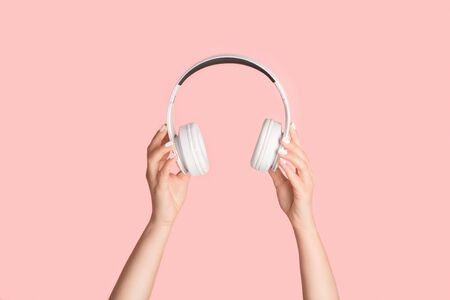 Cropped view of millennial girl holding headphones on pink backgroundの写真素材