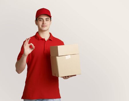 Excellent job. Deliveryman holding parcels in hand and shows sign perfectly with his hand isolated...