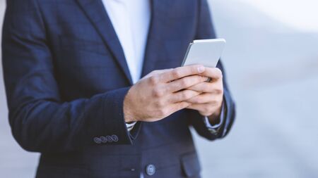 Closeup view of businessman using cellphone in heart of cityの写真素材