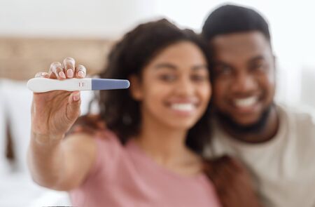 Closeup of positive pregnancy test shown by happy black couple, pregnancy, parenthood conceptの写真素材