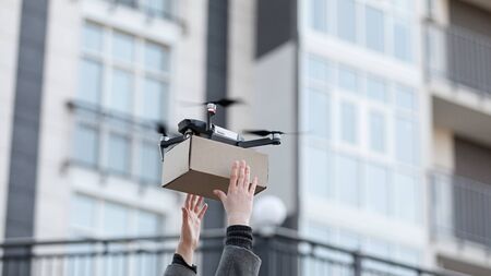 Modern technologies. Woman carrying package from quadrocopter contactless delivery.の写真素材