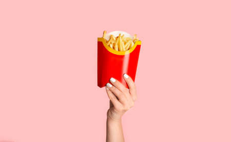 KHARKIV, UKRAINE - APRIL 4, 2020: Female hand showing french fries from McDonalds in red package on...
