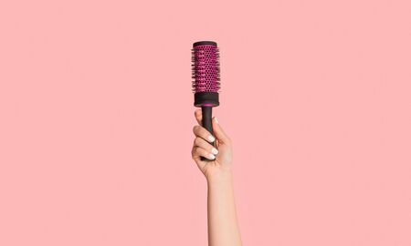 Cropped view of girl holding hair brush on pink background, close up. Panoramaの写真素材
