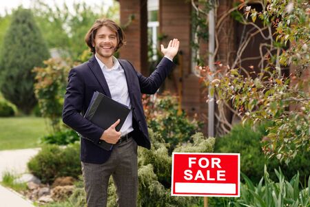 Smiling real estate agent showing house for sale, outdoors. Blank spaceの写真素材
