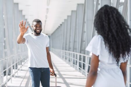 Welcome Back. Loving Wife Meeting Her Black Husband In Airport, Happy Man Waving Hand