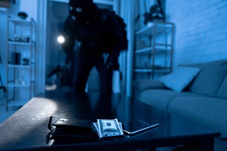 Housebreaking Concept. Thief sneaking into apartment, searching something to steal, using torch, focus on deskの写真素材
