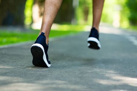 Cropped view of marathon runner working out at park in morning, closeup of legs