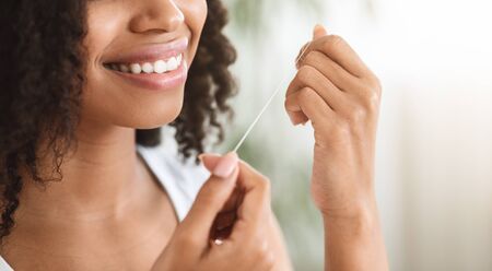 Tooth Care. Unrecognizable black woman with white healthy teeth using dental floss at home, making morning oral care routineの写真素材