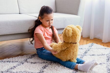 Lonely Kid. Sad Asian Girl Sitting With Teddy Bear Toy Suffering From Loneliness Alone At Home.の写真素材