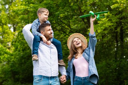 Happy family with adorable little kid playing with toy airplane in woodの写真素材