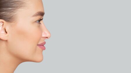 Side view portrait of young beautiful woman with perfect skin looking aside at free space for advert isolated on gray wallの写真素材