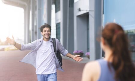 Wife meeting husband at airport terminal, welcoming back home. Man opening arms for hugの写真素材