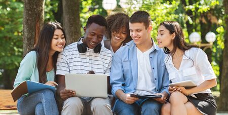List Of Accepted Students. Happy Interracial Teen Friends Using Laptop Outdoors, Checking Results Of Their Exams, Panoramaの写真素材